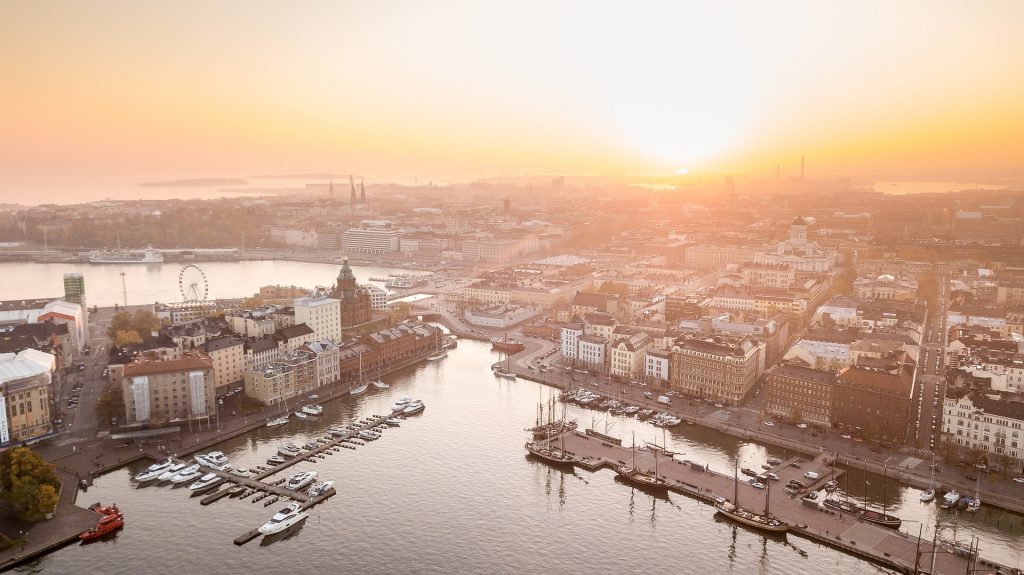 Ilmakuva Helsingistä, jonka taivaanranta on värjäytynyt oranssiksi.